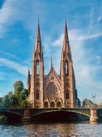 View of church by river against sky