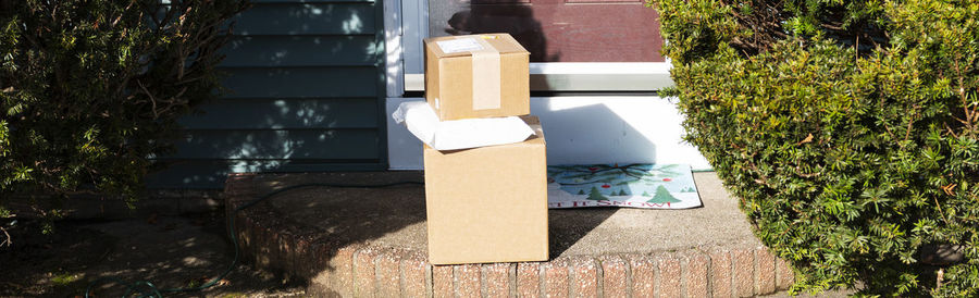 Stack of box by plants on sunny day