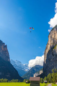 Low angle view of person paragliding against blue sky