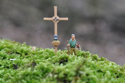 Figurine by cross on moss