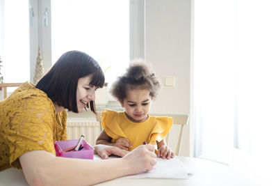 Mother and daughter sitting on table