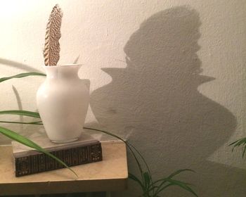 Close-up of vase on table against wall