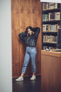 Full length of young woman standing at library