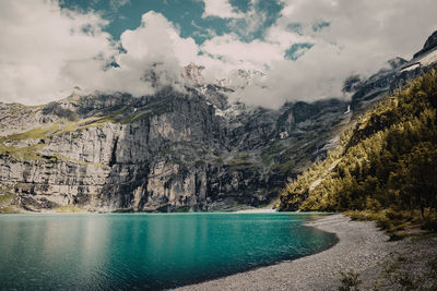 Scenic view of sea by mountain against sky