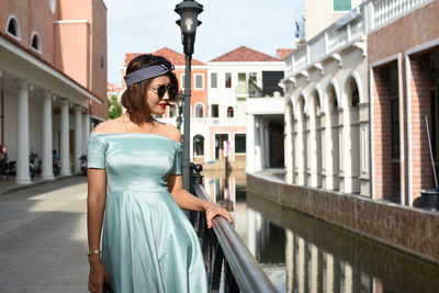 Woman standing at railing while standing in city