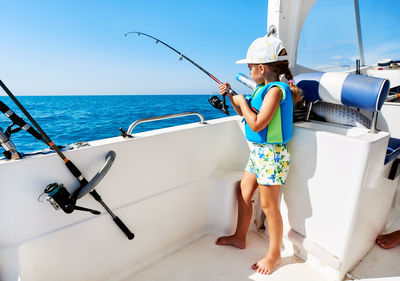 Low angle view of girl standing on boat sailing in sea