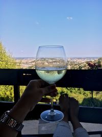 Close-up of woman hand holding wine glass against sky