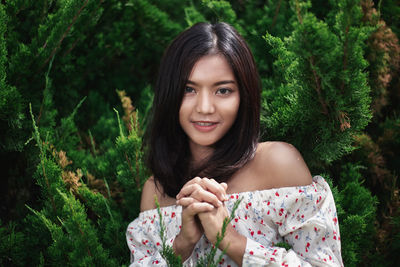 Portrait of young woman against plants