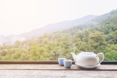 Coffee cup on table against mountains