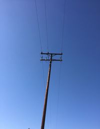 Low angle view of electricity pylon against clear sky