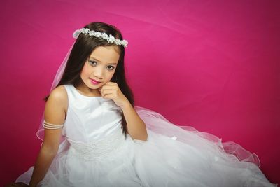 Portrait of smiling young woman standing against pink background