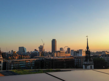 Modern buildings in city against clear sky during sunset