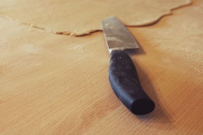 Close-up of kitchen knife by rolled pizza dough on table