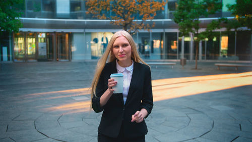 Portrait of young woman standing in city