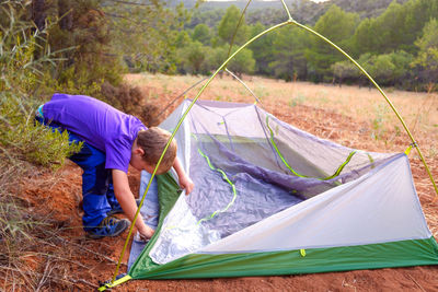 Man holding tent on field