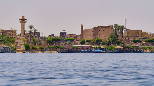 River by buildings in city against clear sky