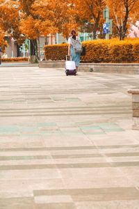 Man sitting on footpath during autumn