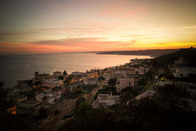 High angle view of townscape by sea against sky during sunset