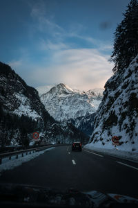 Road by snowcapped mountains against sky