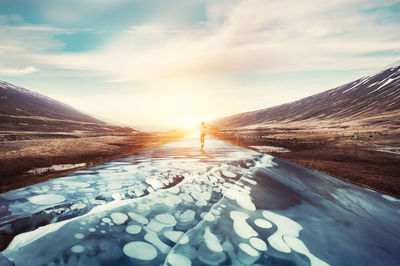 Snow covered landscape against sky during sunset