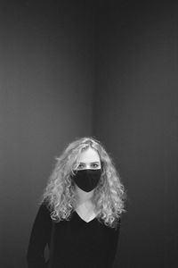 Portrait of young woman standing against wall