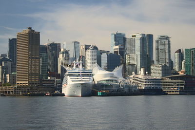 Modern cityscape by sea against sky