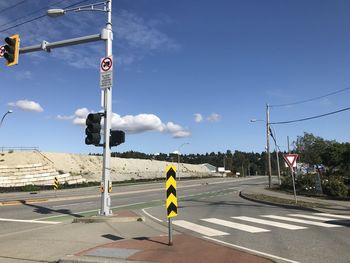 Road sign on street against sky