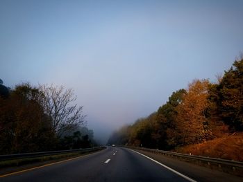 Road amidst trees against clear sky