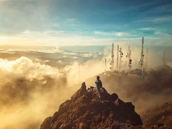 People sitting on rock against sky