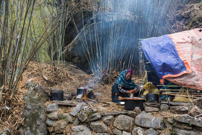 Panoramic view of people sitting on rock in forest