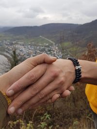 Cropped image of friends holding hands against mountains