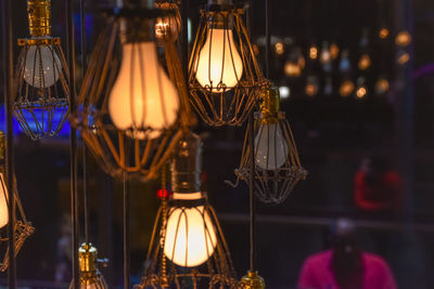 Close-up of illuminated lighting equipment hanging at store