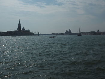 Sailboats in sea against sky in city