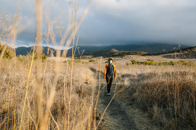 Man walking on field against sky