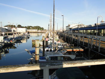 Boats moored at harbor against sky