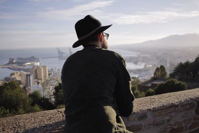 Rear view of man looking at cityscape and bay