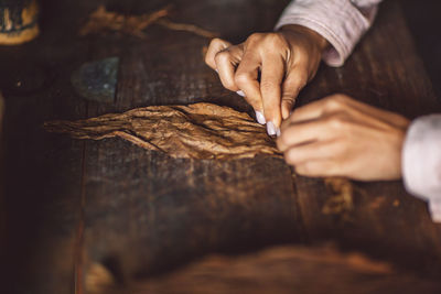 Close-up of hands rolling tobacco on table