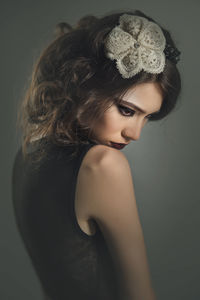 Beautiful young woman wearing hair clip in brown hair against gray background