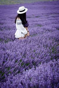 Full length of young woman with flowers on field