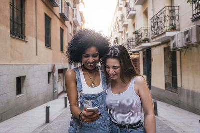 Smiling young woman using mobile phone in city