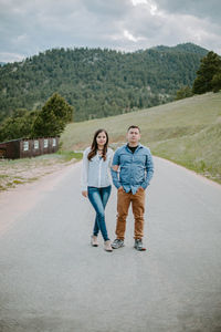 Full length portrait of young woman and man standing on road