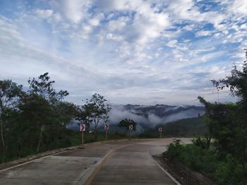 Road by trees against sky