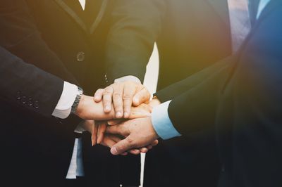 Midsection of businesspeople hands in huddle