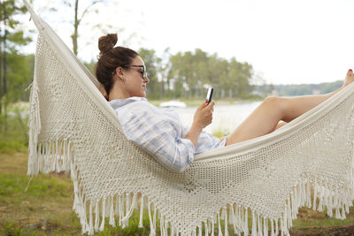 Woman using phone on hammock barefoot