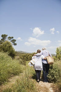 Full length of couple with picnic basket and blanket going for picnic