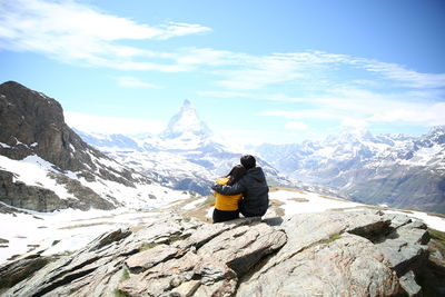Rear view of man on snowcapped mountain against sky