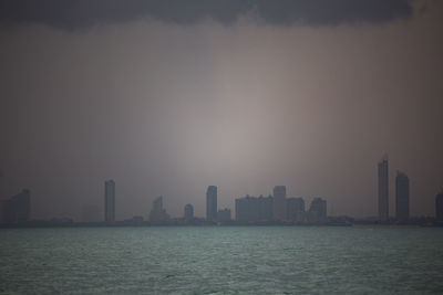 Sea by buildings against sky in city