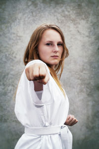 Portrait of woman punching against wall