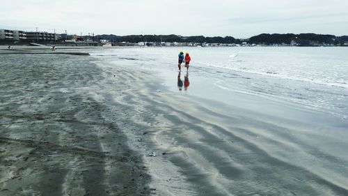 People on beach against sky during winter