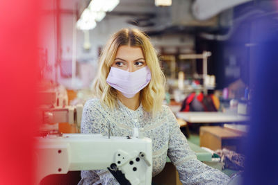 Woman wearing mask while working in factory